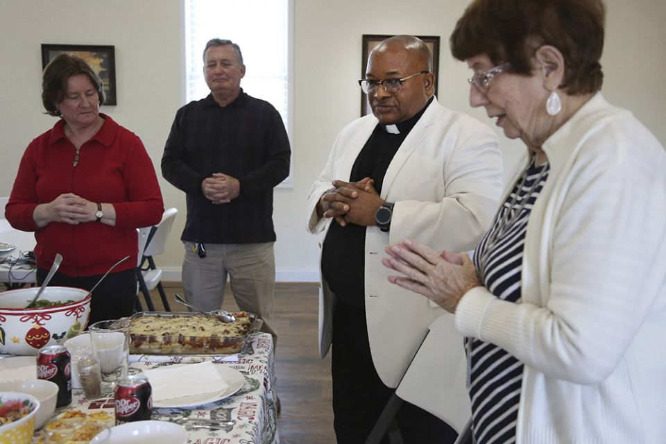 Michele and Frank Varisco, left, pray with Fr. Athanasius Abanulo and Evelyn Smith, right, before eating lunch at Immaculate Conception Catholic Church in Wedowee, Alabama, on Sunday, Dec. 12, 2021. (AP/Jessie Wardarski)