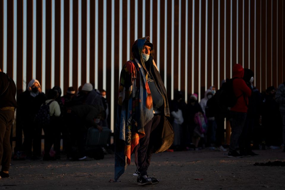 Migrants seeking asylum in Yuma, Ariz., Jan. 23, 2022, stand near the border fence while waiting to be processed by the U.S. Border Patrol. (CNS photo/Go Nakamura, Reuters)