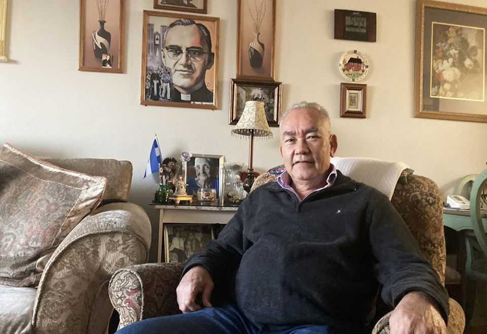 Jesús Aguilar, de 65 años, se sienta para un retrato en su casa en Los Ángeles, frente a una imagen de San Oscar Romero. (RNS foto por Alejandra Molina)