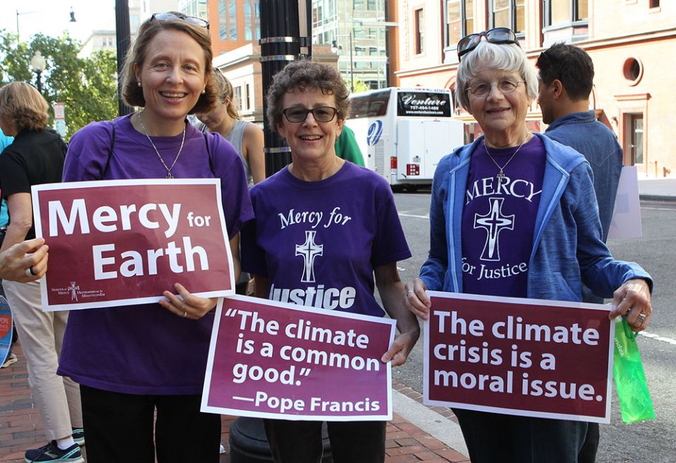 Mercy Sister Aine O'Connor, Marianne Comfort, justice coordinator for the Mercy Sisters, and Mercy Sister Rita Parks hold aloft signs Sept. 20, 2019, in front of St. Patrick's Church in Washington as they prepare to join a climate change march. (CNS)