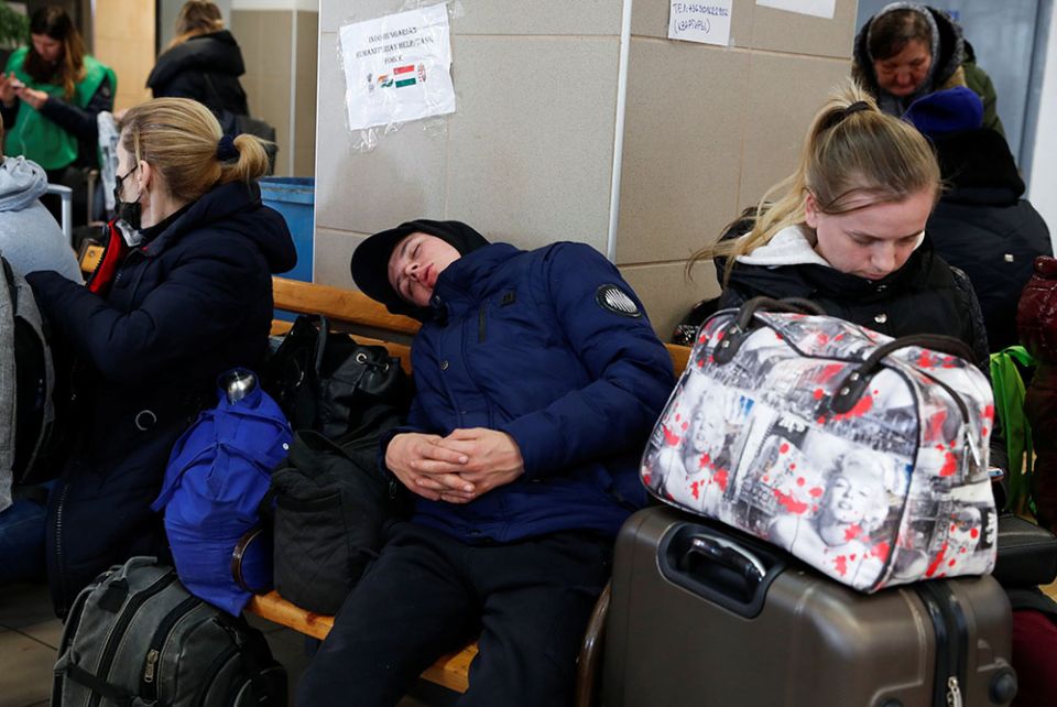 A boy fleeing Russia's invasion of Ukraine sleeps at a train station in Zahony, Hungary, March 15. (CNS/Reuters/Bernadett Szabo)