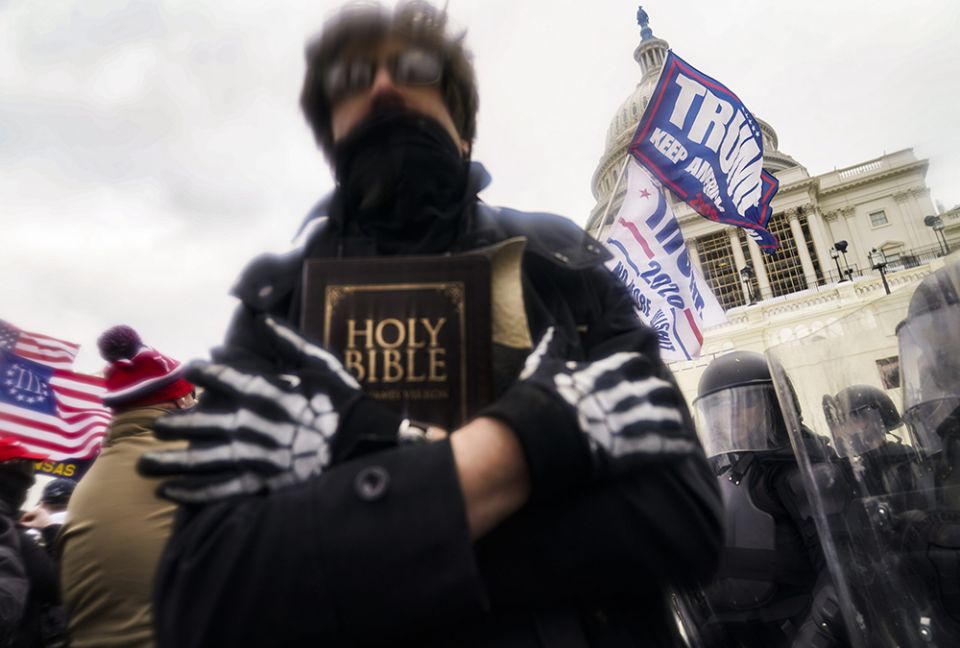 In this Jan. 6, 2021, file photo, a man holds a Bible as Trump supporters gather outside the Capitol in Washington. (RNS/AP photo/John Minchillo)